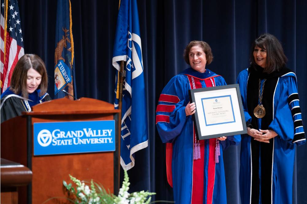 Recipient stands next to President holding her award on stage